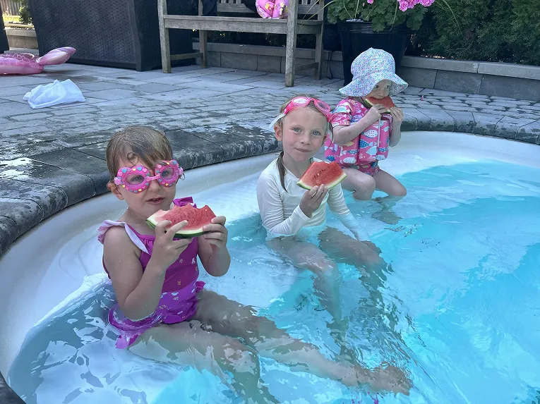 Children eating watermelon in the pool